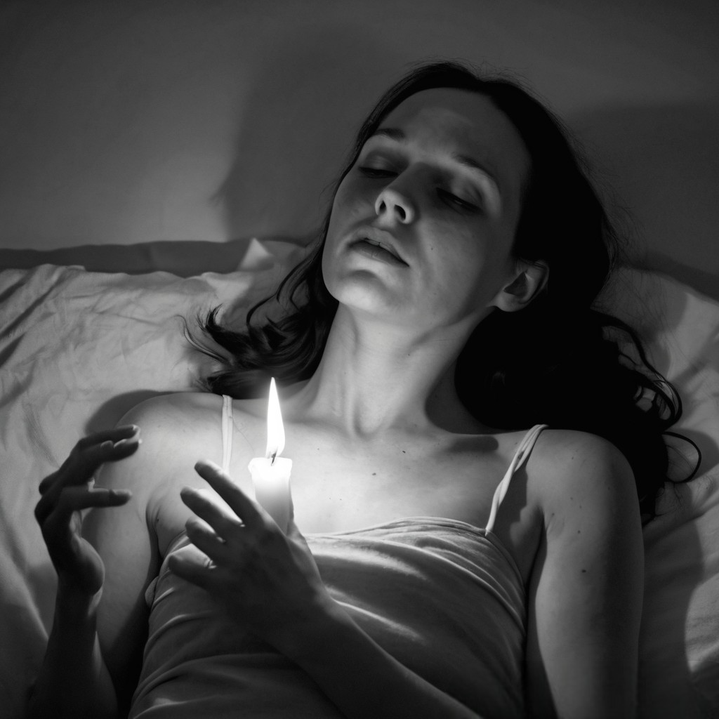 Donna in penombra, avvolta da una luce soffusa, in un momento intimo di resa e desiderio interiore.